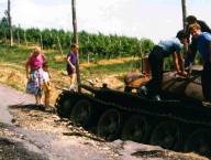 Na in ob uničenem tanku jugoslovanske armade stojijo Kogovčani.